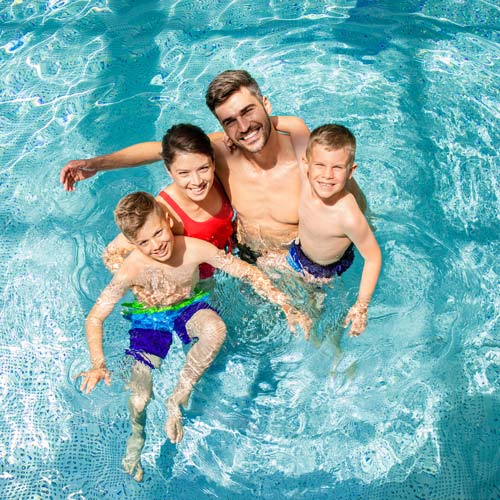 Familie genießt den Pool – Nachhaltige Poolnutzung mit Poolabdeckung – Umweltfreundlicher Poolbetrieb durch weniger Verdunstung und reduzierte Heizkosten.