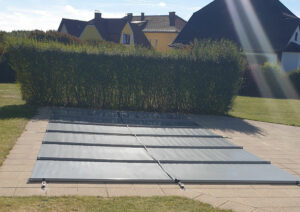 Mittelgraue Poolabdeckung als zuverlässiger Schutz gegen Schmutz, Laub und Wärmeverlust.