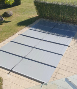 Mittelgraue Poolabdeckung schützt das Wasser vor Schmutz und reduziert die Verdunstung.