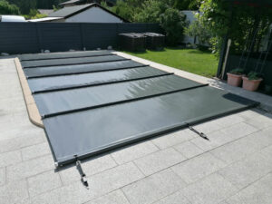 Dunkelgraue Poolabdeckung schützt das Wasser vor Schmutz und reduziert die Verdunstung.