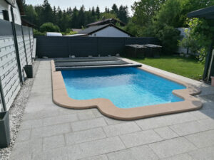 Teilweise geöffnete dunkelgraue Poolabdeckung auf einem eingelassenen Pool mit modernem Design.