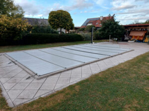 Hochwertige hellgraue Poolabdeckung schützt den Pool vor Schmutz, reduziert Wasserverdunstung und senkt Heizkosten.