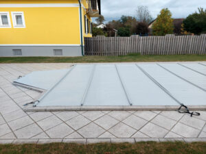 Robuste hellgraue Poolabdeckung schützt den Pool vor Schmutz, reduziert Wasserverdunstung und trägt zur Wärmespeicherung bei.