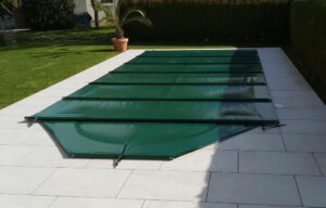 Pool mit dunkelgrüner Stangenabdeckung und Römertreppe – effektiver Schutz vor Schmutz, Verdunstung und Energieverlust.