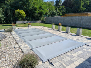 Mittelgraue Poolabdeckung mit Stangen – Schutz vor Schmutz, Verdunstung und ungewolltem Hineinfallen.