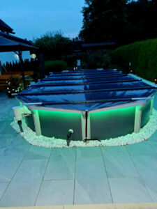 Pool mit dunkelgrauer Stangenabdeckung in der Nacht, stilvoll beleuchtet für mehr Sicherheit und Energieeinsparung.